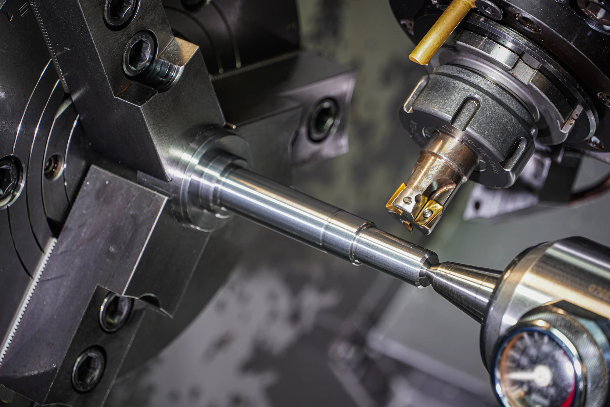 Close-up of a CNC lathe turning a polished steel shaft, carbide cutter poised above the part