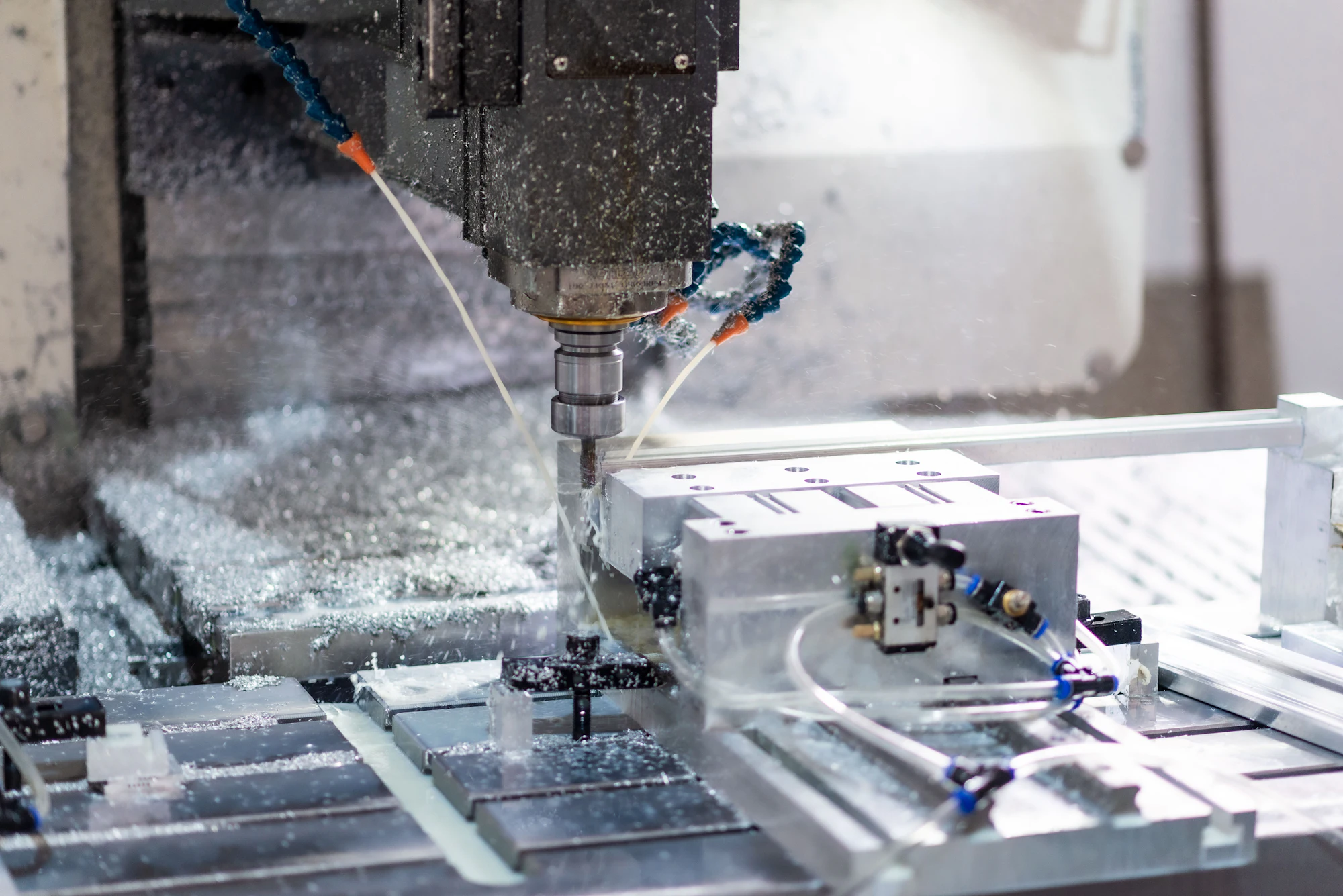 CNC mill cutting an aluminum workpiece under coolant spray, chips flying off the tool
